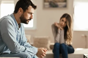 man feeling sad after arguing with his girlfriend on sofa at home